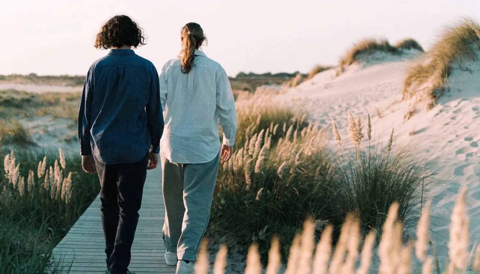 Two people walking calmly along a Florida beach path at golden hour